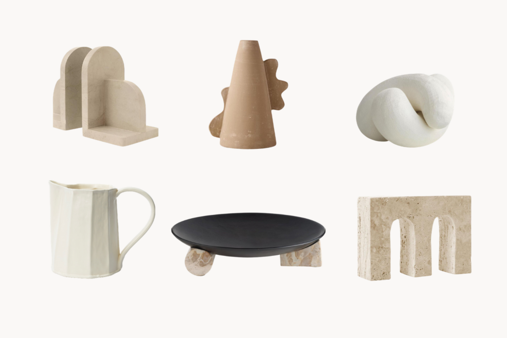 Neutral toned ceramic sculpture set arched blocks a cone with gear like protrusion a twisted loop form a white pitcher a black round plate on stone bases and a beige arch block